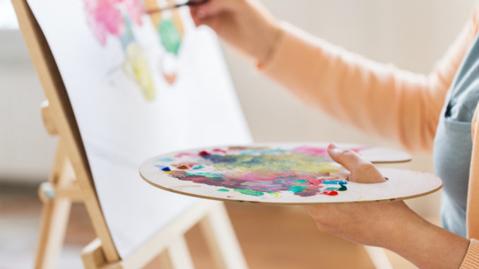 artist with palette and brush painting at studio arteterapia